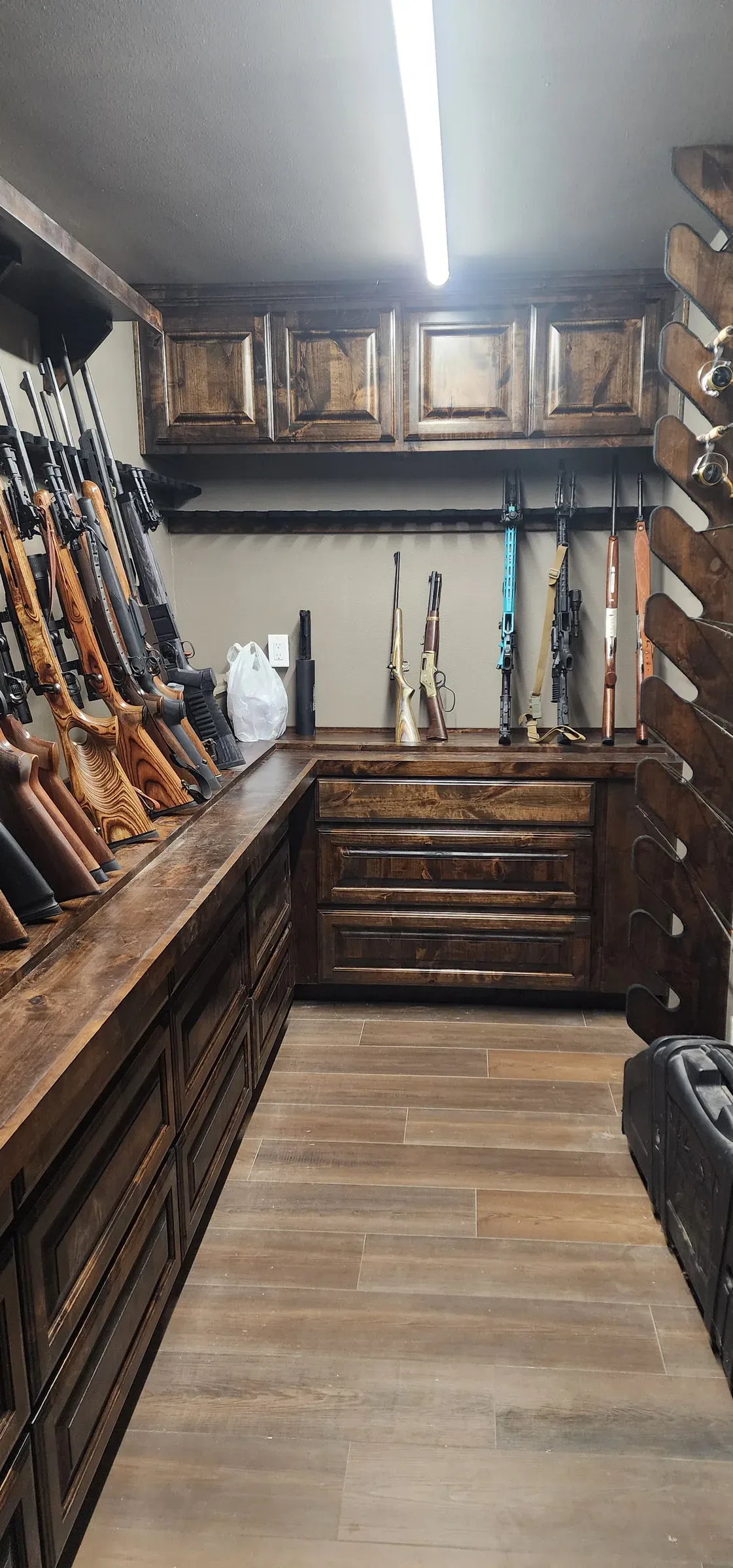 Custom gun room with wall-mounted rifle racks, upper cabinets, and a wraparound drawer base
